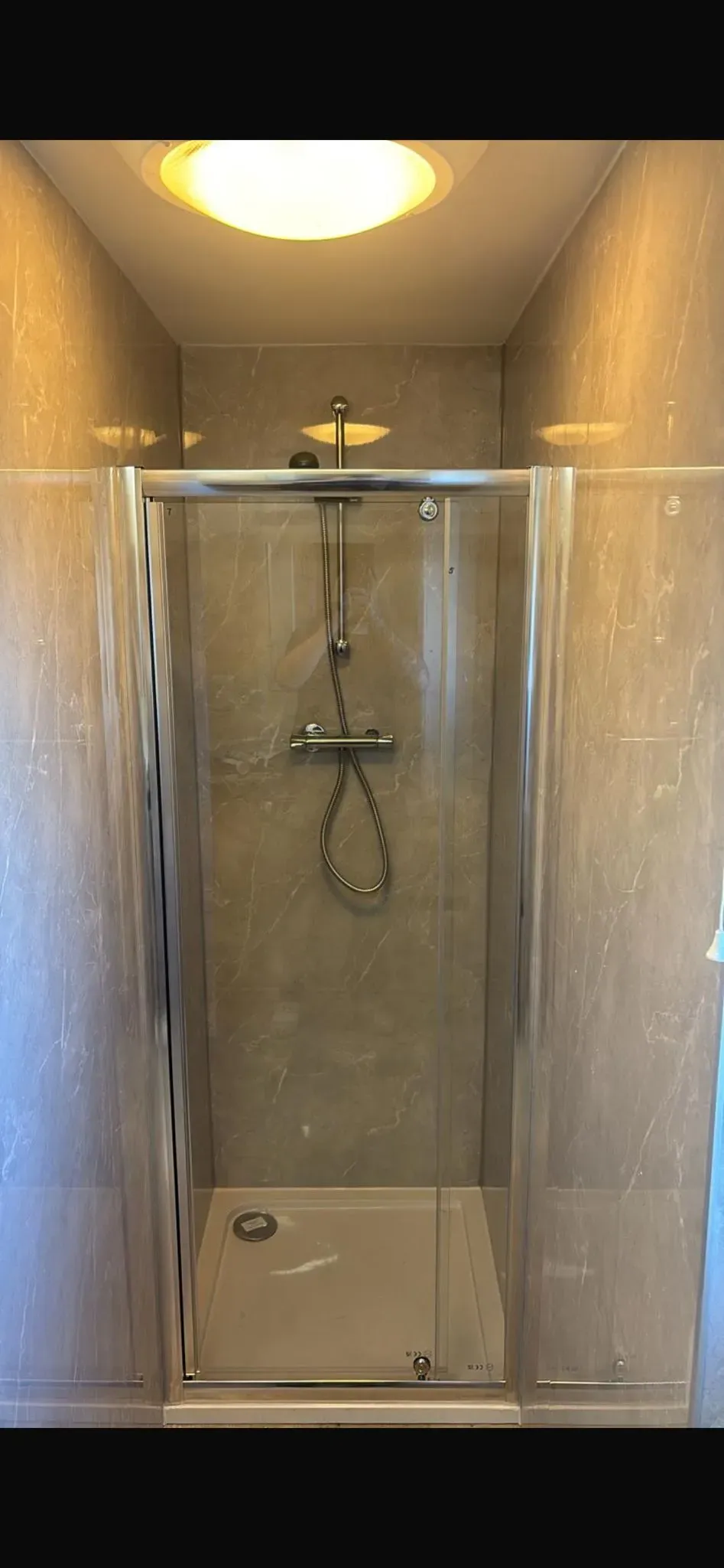 A modern shower enclosure installed in a tiled bathroom.
