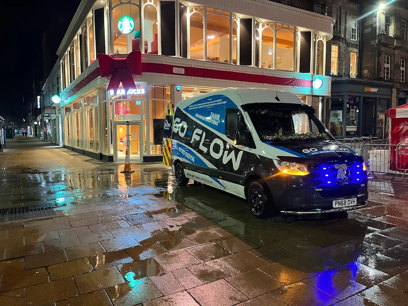 A GO-FLOW Drainage Solutions van parked on a wet street at night
